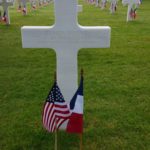 Grave marker of a WWII soldier with an American and French flags in front of it