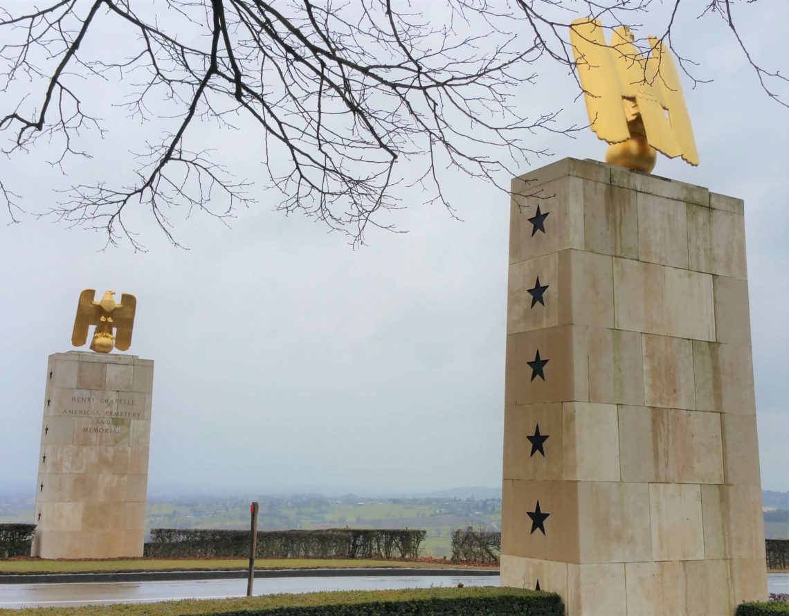 Henri-Chapelle American Cemetery entrance with stone towers and gold eagles