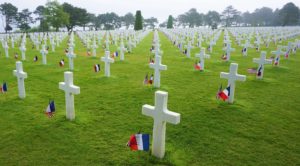 view of hundreds of grave markers at the Normandy american cemetery with american and french flags