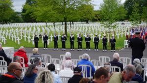 soldiers standing at attention with white crosses in the background